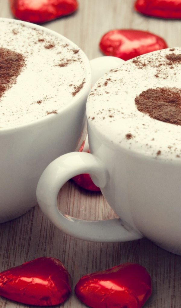 Две чашки кофе на столе с шоколадными конфетами в форме сердца