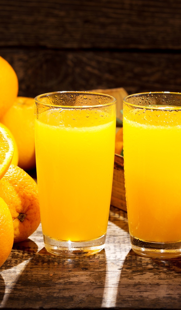 Два стакана свежего апельсинового сока на столе с фруктами