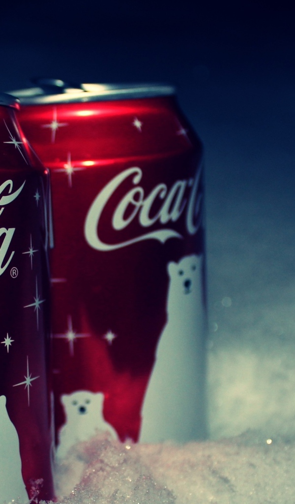 Две красные банки напитка Кока Кола стоят на снегу