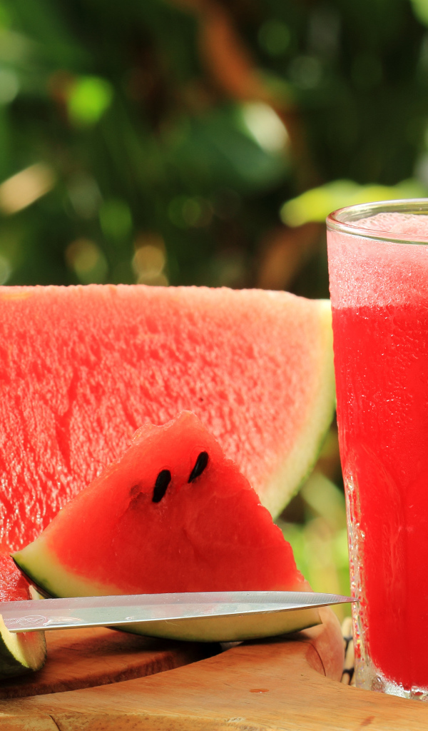 Арбузный напиток в стакане на столе с куском арбуза