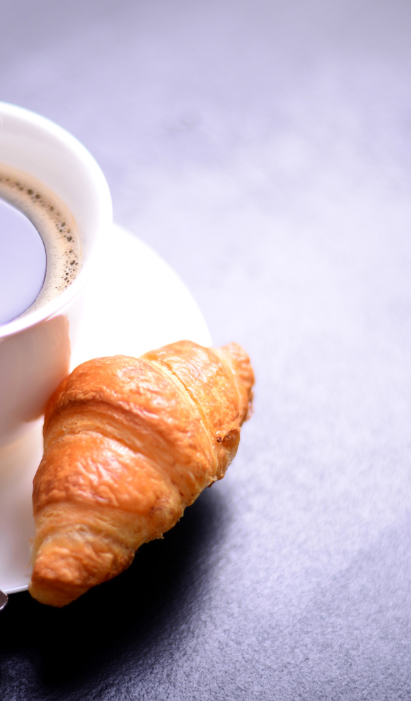 Белая чашка кофе на столе с круассаном