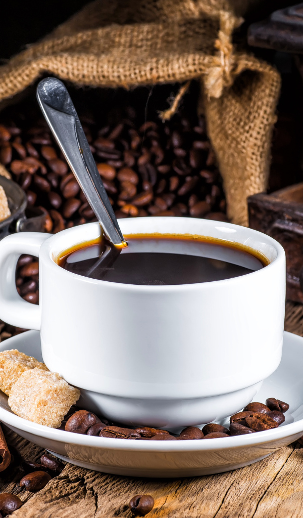 Белая чашка кофе на столе с сахаром, корицей и бадьяном 