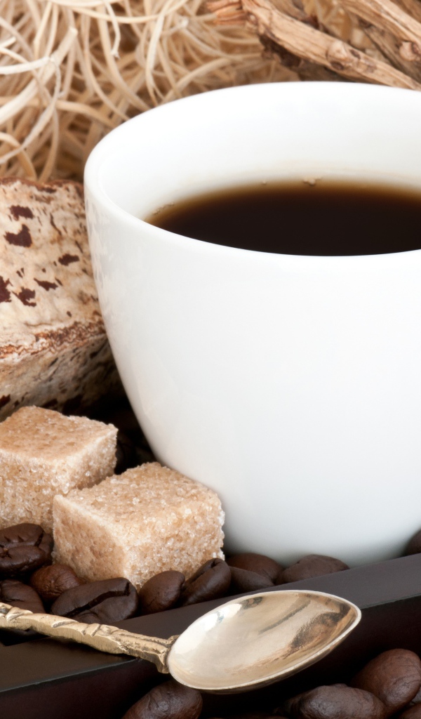 Белая чашка кофе с зернами и кусочками сахара на столе 