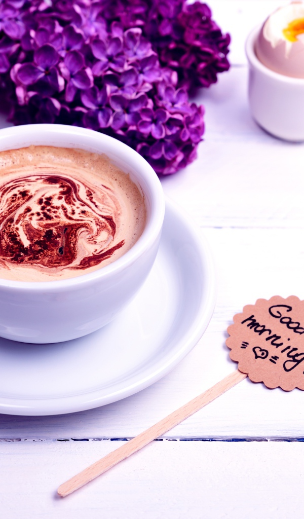 Белая чашка кофе с цветами сирени и яйцом на завтрак