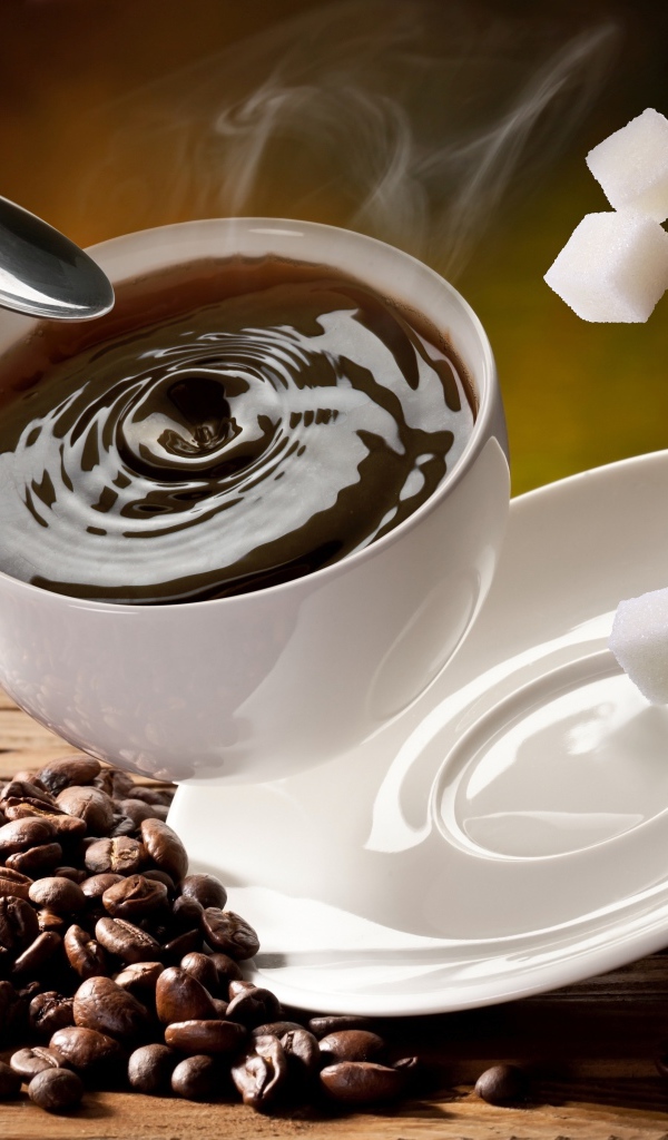 Белая чашка с кофе падает на стол с кофейными зернами