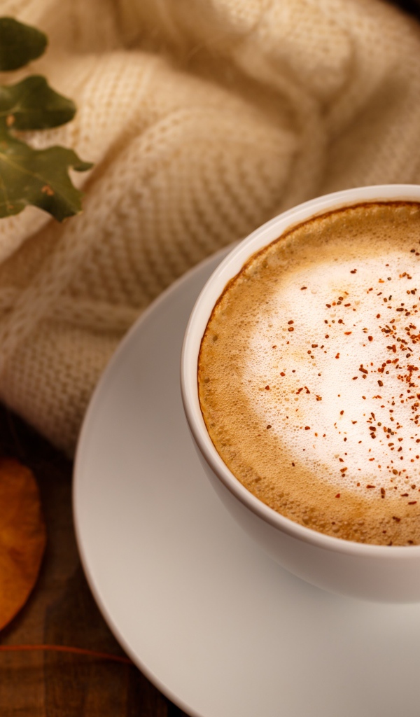 Белая чашка с вкусным кофе на столе с желтыми листьями