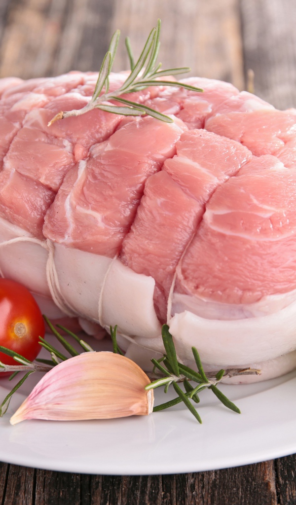 Кусок свежего мяса со свежими помидорами, чесноком и листьями салата