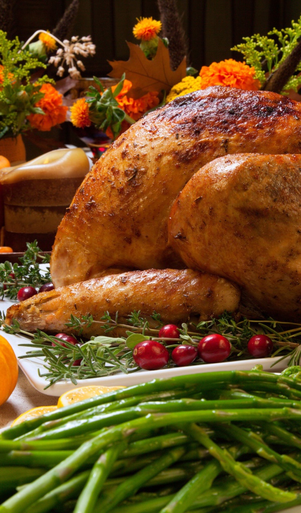 Аппетитная запеченная курица с зеленой спаржей и угощениями на праздничном столе