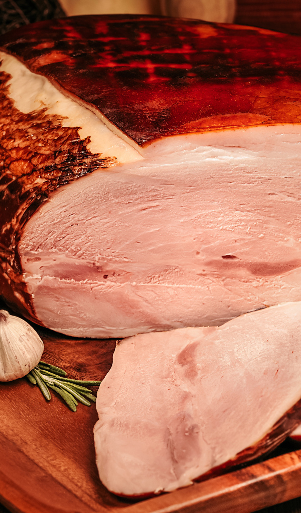 Аппетитный кусок ветчины с перцем и чесноком на доске