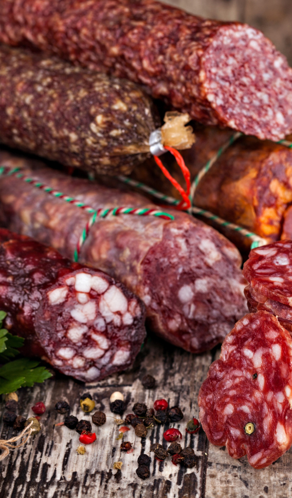 Аппетитная колбаса на столе с чесноком и черным перцем