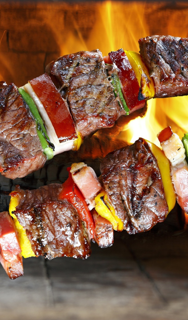 Аппетитный шашлык с овощами на фоне огня