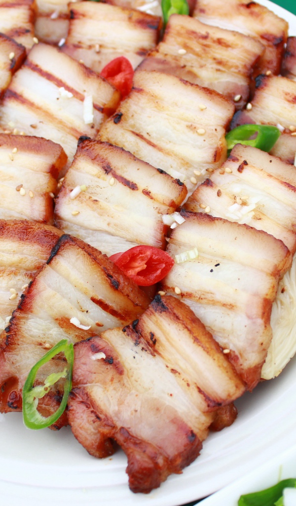 Аппетитное копченое сало на столе с овощами