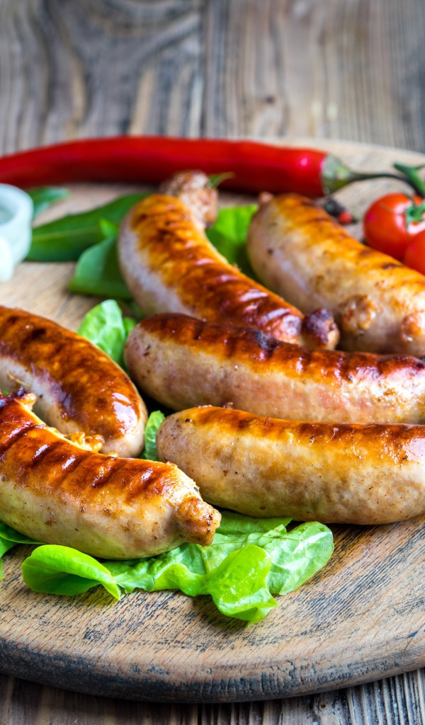 Сосиски барбекю с красным перцем и помидорами на разделочной доске