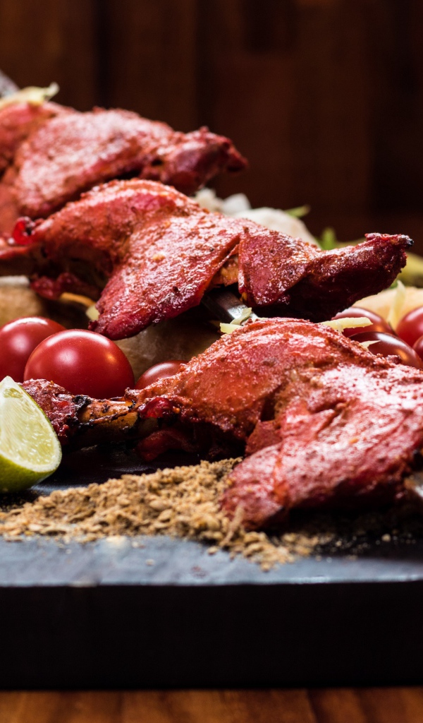 Курица жареная на шампурах на столе с овощами 