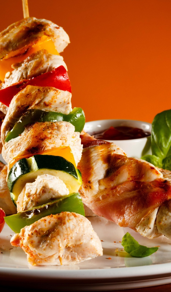 Куриные шашлыки с овощами на белой тарелке