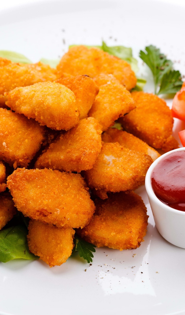 Куриные наггетсы с соусом и помидорами на белой тарелке 