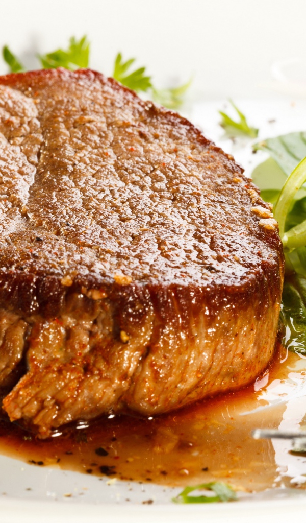 Отбивная с зеленым салатом на тарелке с вилкой