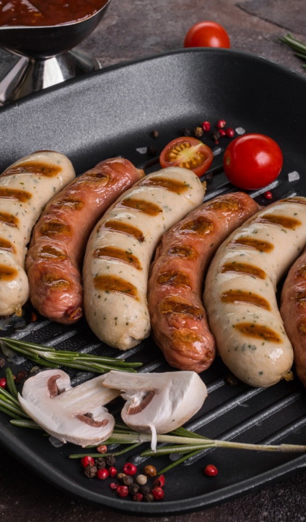 Колбаски гриль на столе с овощами 