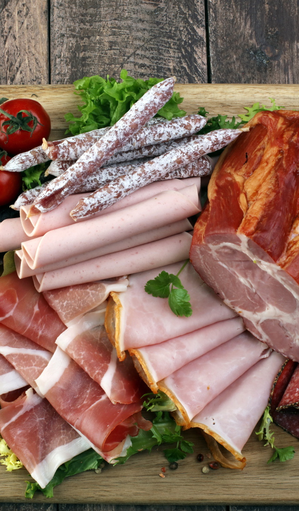 Мясная нарезка на разделочной доске с помидорами