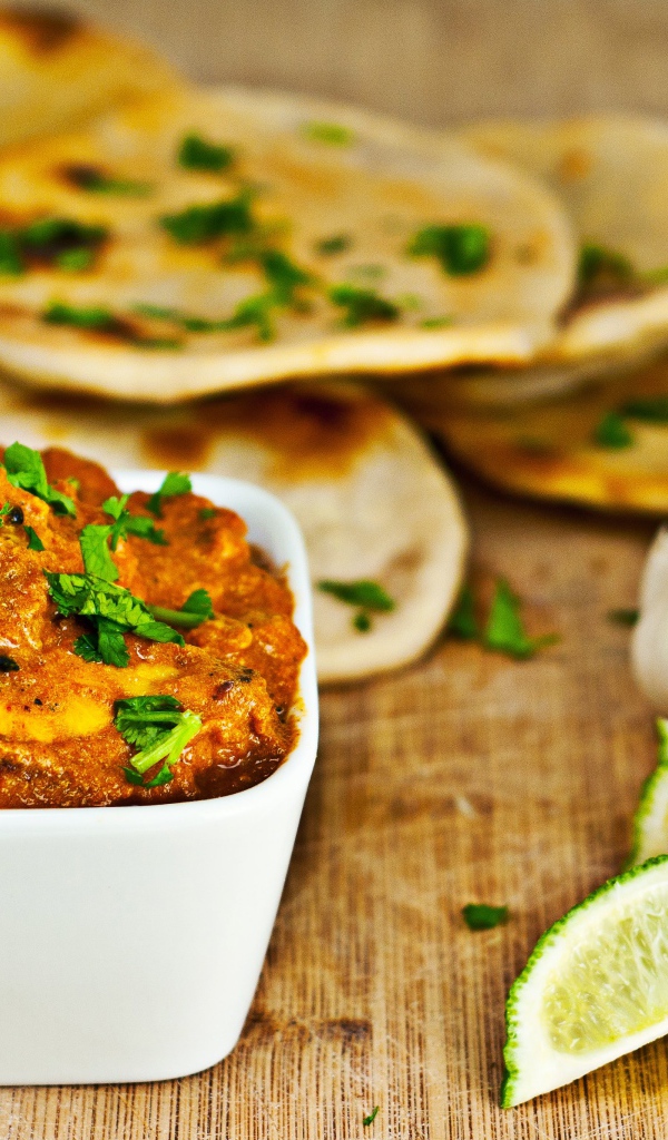 Мясное блюдо на столе с лепешками, кусочками лайма и чесноком