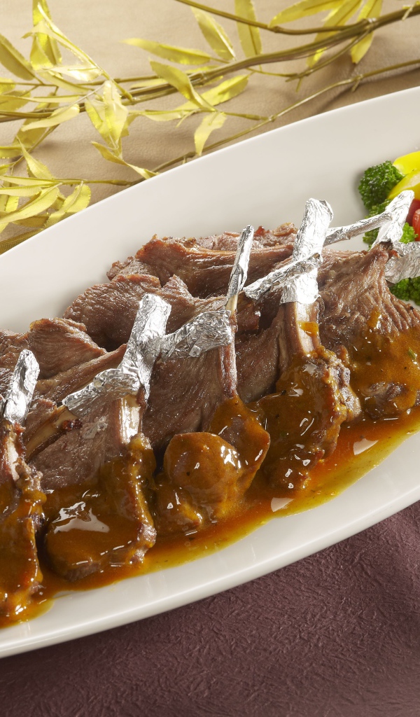 Мясо на белой тарелке с соусом и овощами 