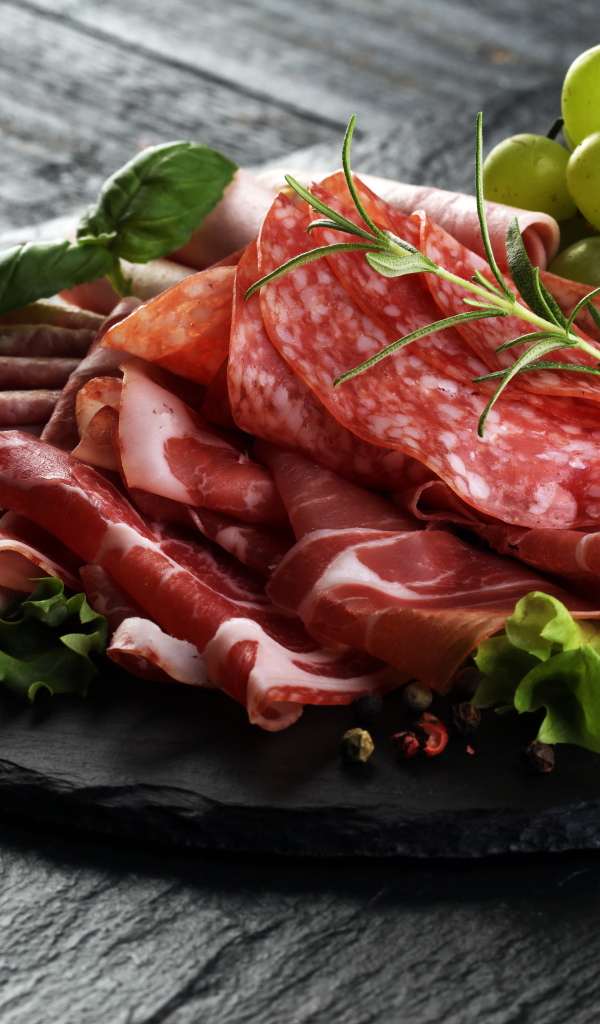 Мясная нарезка с листьями салата и белым виноградом 