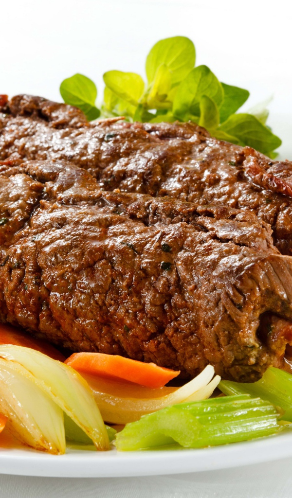 Свинина на тарелке с овощами на белом фоне