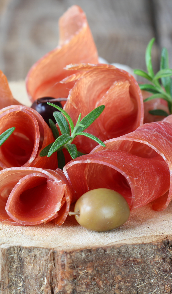 Прошутто  с оливками на деревянном столе 