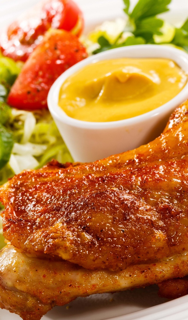 Жареная куриная ножка с овощами и соусом на тарелке