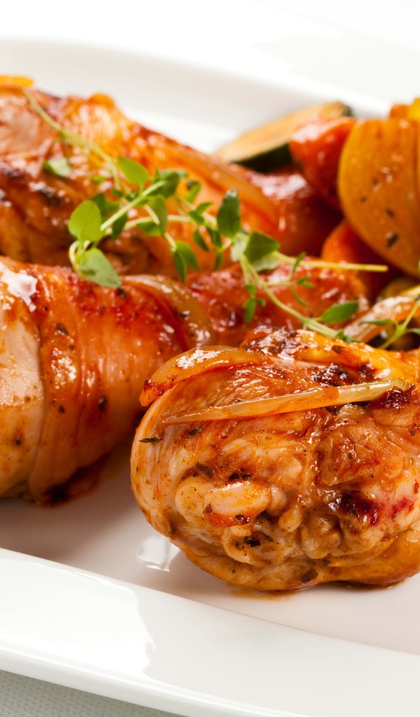 Жареные куриные ножки с овощами на белом фоне