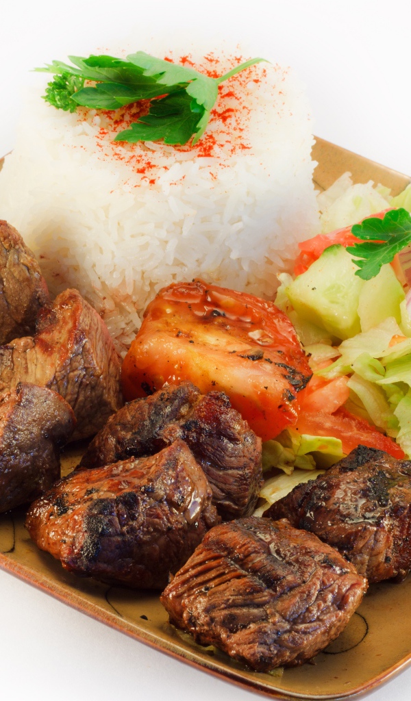 Шашлык с рисом и овощами в тарелке на белом фоне