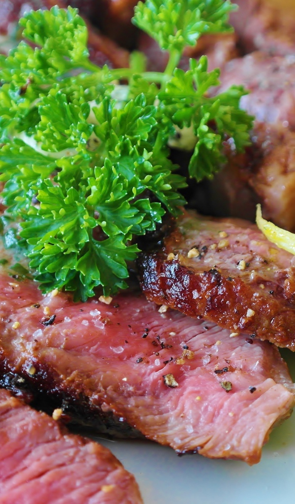 Нарезанный аппетитный кусок мяса с салатом и зеленью петрушки