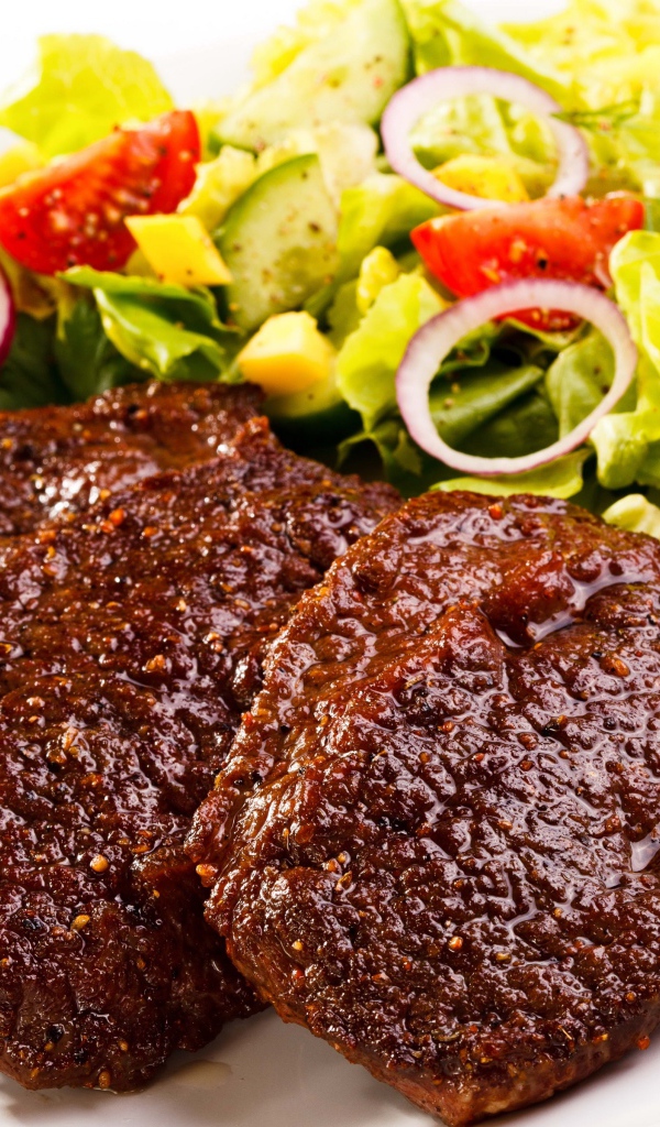 Три котлеты на тарелке с салатом на белом фоне