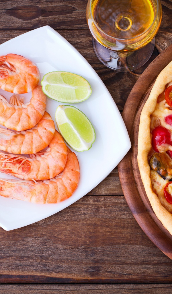 Аппетитная пицца на столе с креветками и кусочками лайма 