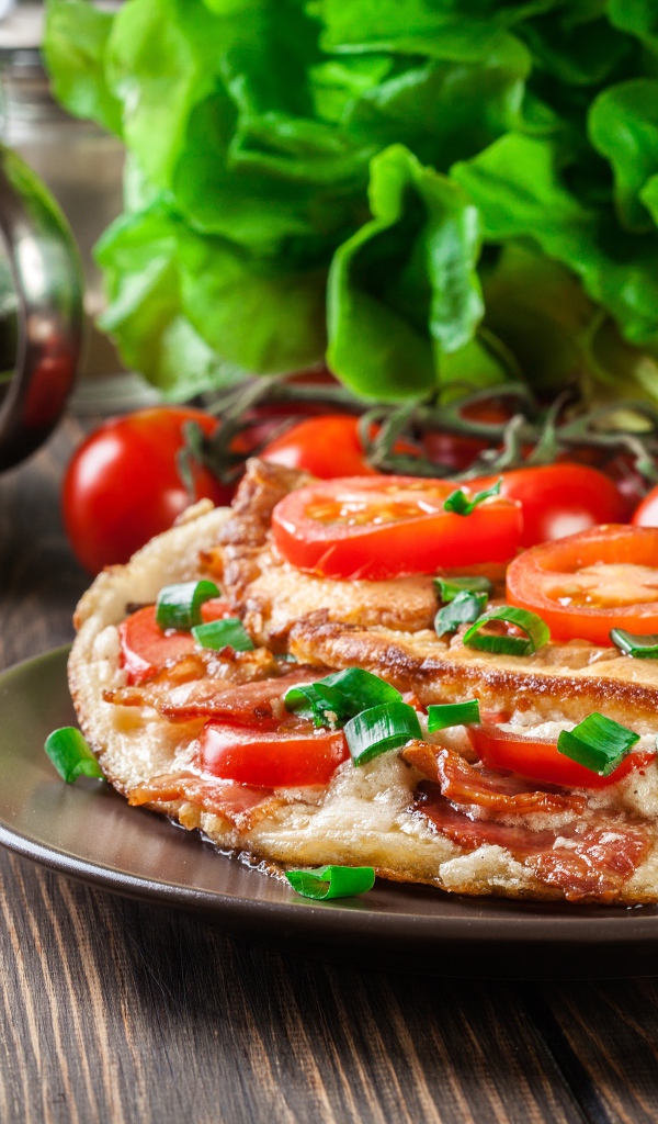 Пицца с помидорами на столе с чаем и зеленью 