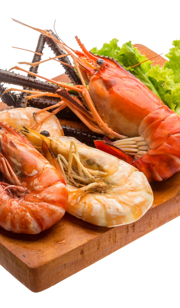 Вареные креветки с листьями салата на разделочной доске