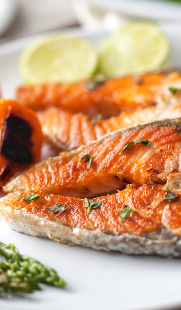 Куски жареной рыбы на тарелке со спаржей и жареным перцем 