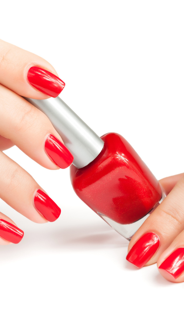 Женские руки с красным маникюром и лаком на белом фоне