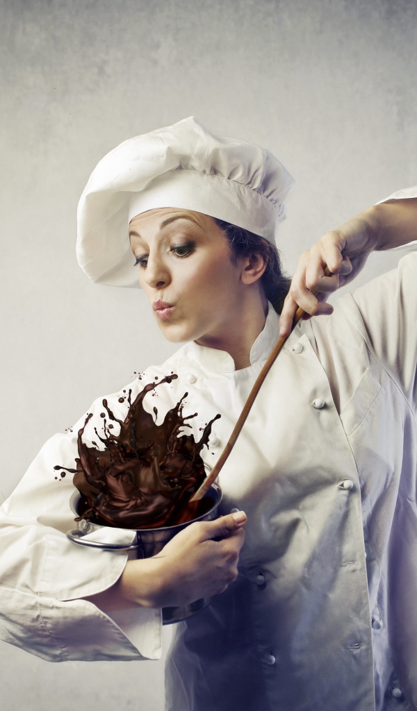 Женщина повар мешает шоколад в посуде на сером фоне