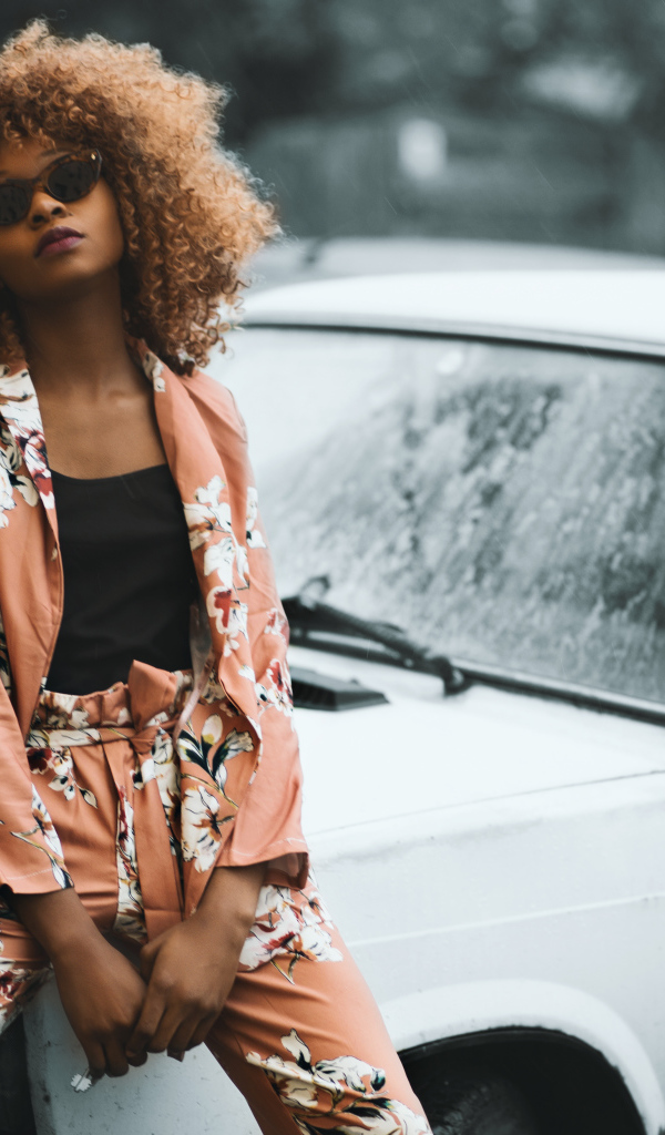 Красивая темнокожая девушка сидит на автомобиле 