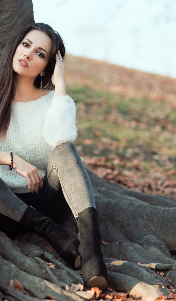 Красивая девушка сидит у дерева