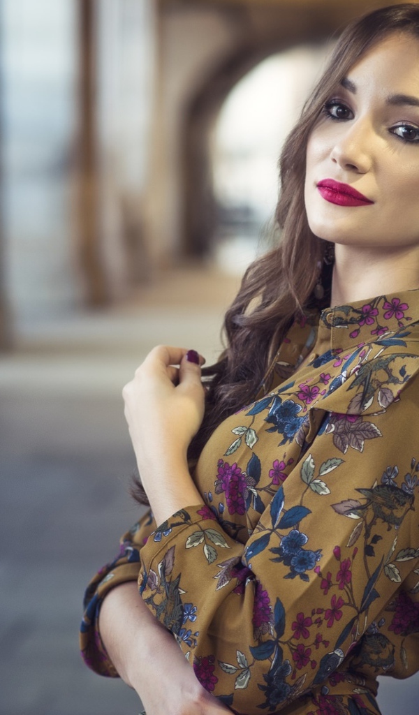 Девушка шатенка в красивом платье у стены