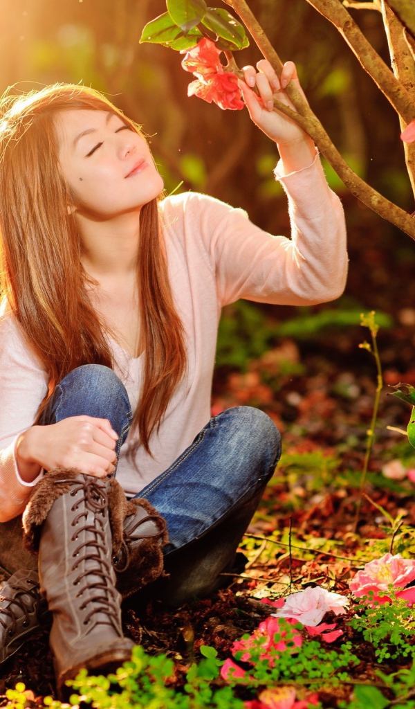 Девушка сидит на земле под ярким солнцем в лесу