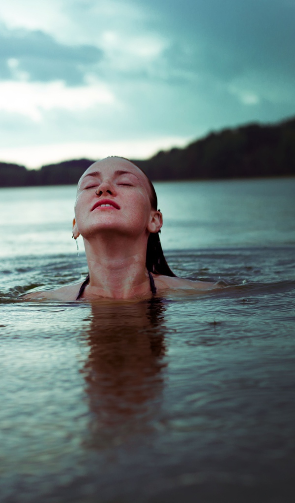 Молодая девушка купается в озере 