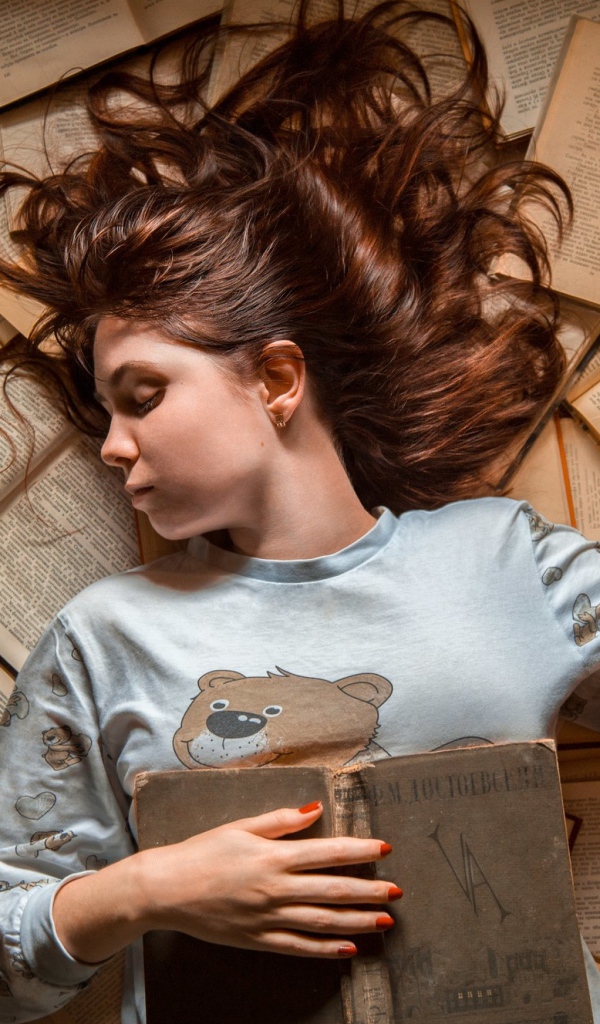 Молодая девушка спит на книгах