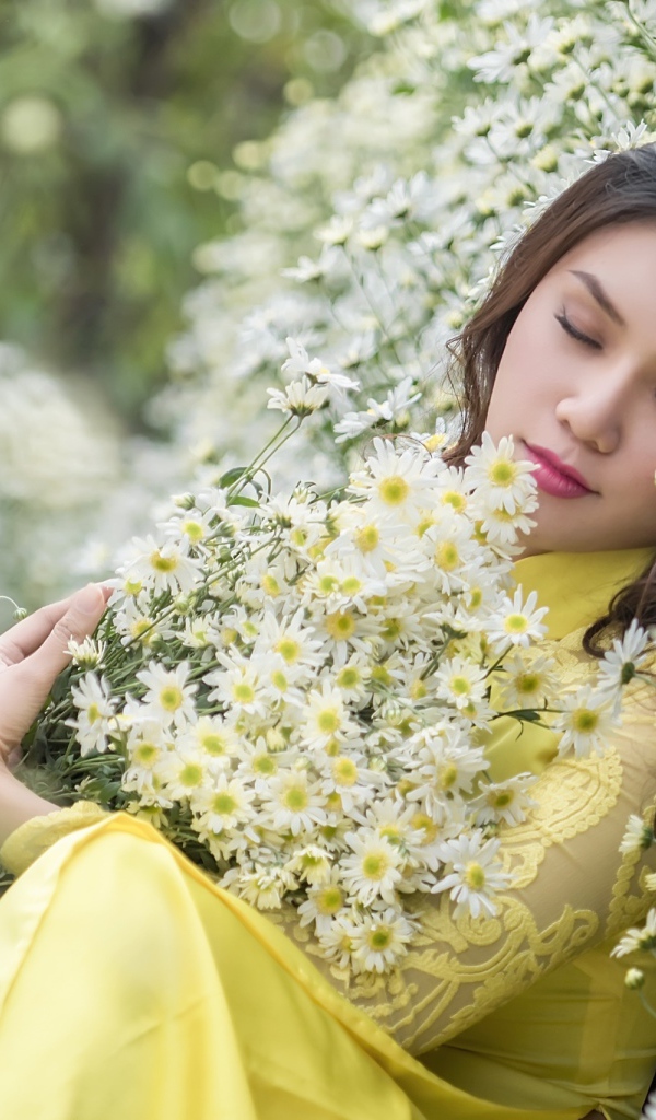 Молодая девушка лежит с букетом белых ромашек