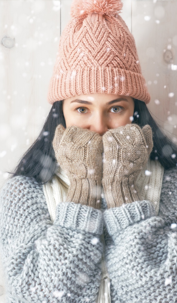 Молодая девушка с теплом свитере с шапкой на голове и перчатках