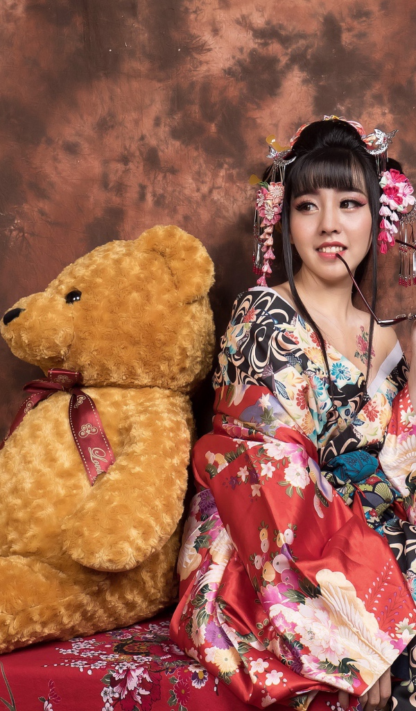Девушка азиатка сидит с большим плюшевым медведем