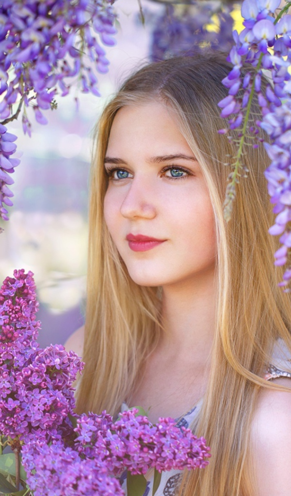 Красивая блондинка с букетом сирени на фоне цветов глицинии