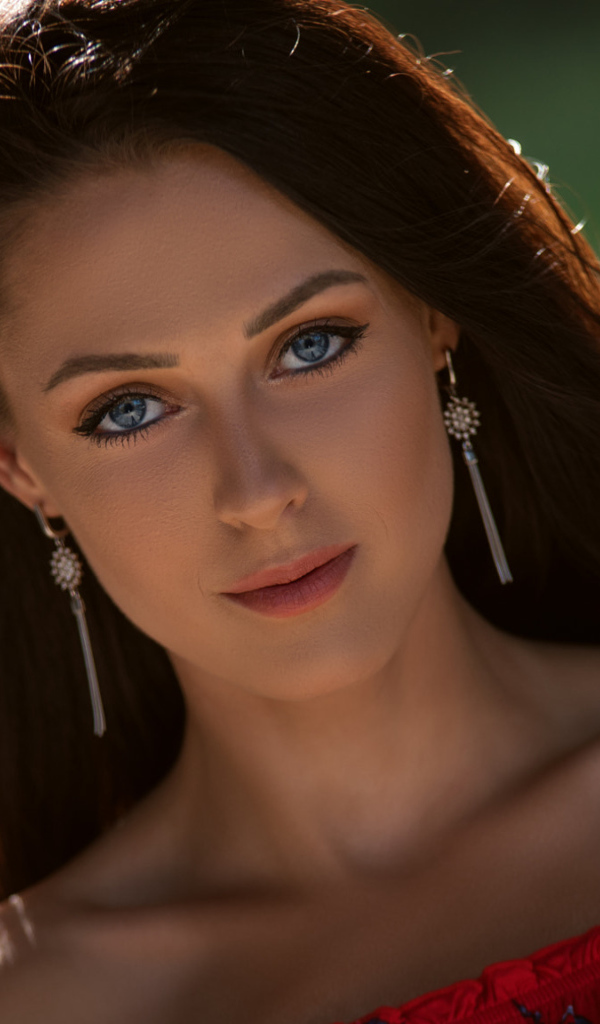 Красивая голубоглазая брюнетка с серьгами у ушах